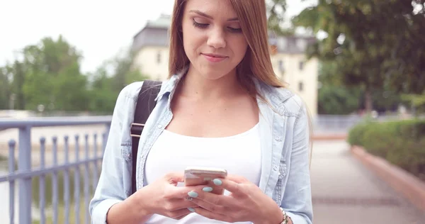 Молодая женщина с телефоном гуляет по улице — стоковое фото
