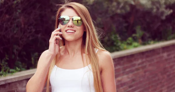 通りで歩いている電話を持つ若い女性 — ストック写真