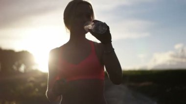 Güzel sarışın kadın gün batımında sahada koşuyor ve egzersiz yapıyor.