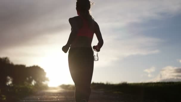 Pretty blonde woman running and exercising on the field during the sunset — Stock Video