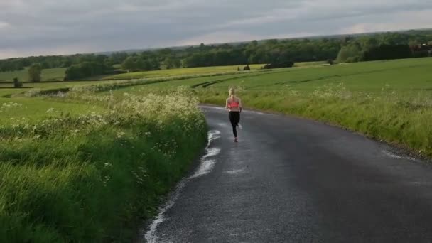 Pretty blonde woman running and exercising on the field during the sunset — Stock Video