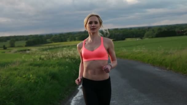 Красивая блондинка бегает и тренируется на поле во время заката — стоковое видео