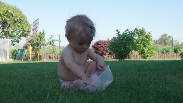 Хлопчик розважається граючи з мискою на траві — стокове відео