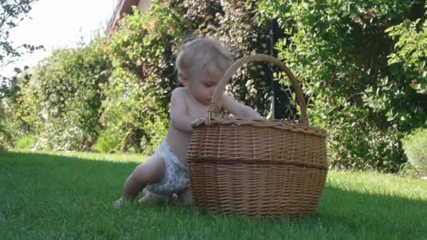 Мальчик весело играет с корзиной, пробуя первые шаги — стоковое видео