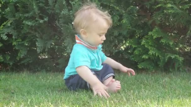 Kleine baby jongen met plezier en glimlachend op het gras — Stockvideo