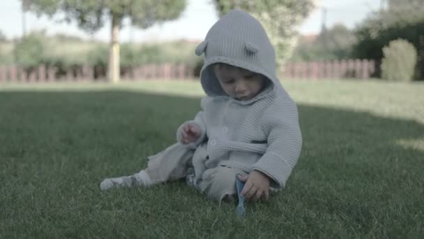 Little Baby Boy zabawy i uśmiecha się na trawie — Wideo stockowe