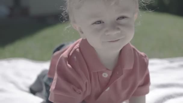 Μικρό αγοράκι που διασκεδάζει και χαμογελάει στο γρασίδι — Αρχείο Βίντεο