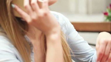 Kafede akıllı telefon kullanan genç bir kadın.