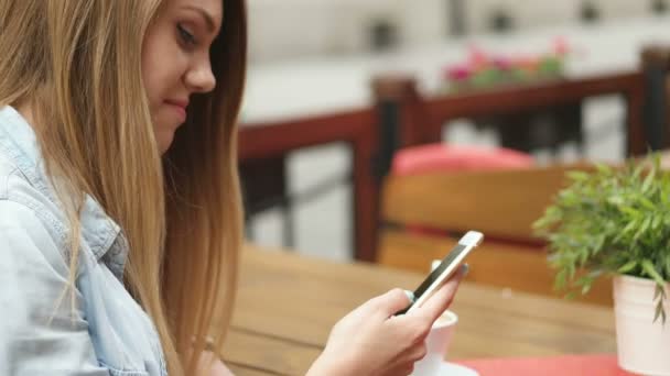 Mujer joven usando teléfono inteligente en la cafetería — Vídeo de stock