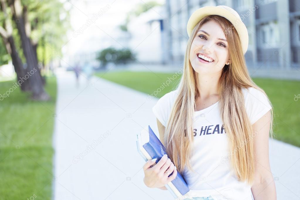 Cheerful Student Girl Holding Books at the Walkway