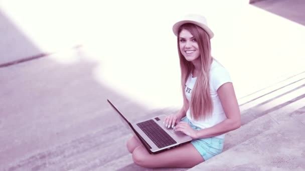 Young woman using laptop on steps outdoors — Stock Video