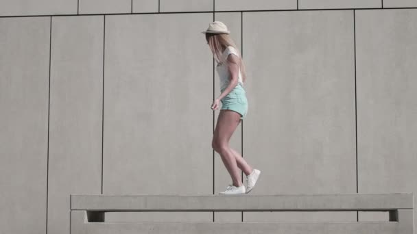 Mujer joven enérgica en traje de fitness, haciendo ejercicio usando cuerda de salto contra fondo de pared blanca en un clima soleado . — Vídeo de stock