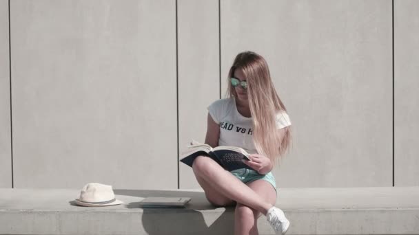 Frau liest Buch auf Bank und lächelt glücklich in die Kamera — Stockvideo