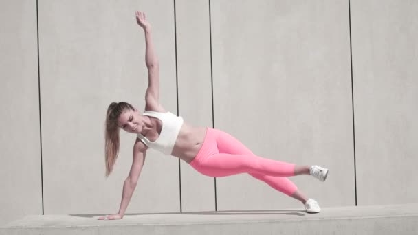 Plankenübung mit erhobenem Arm auf weißer Plattform — Stockvideo