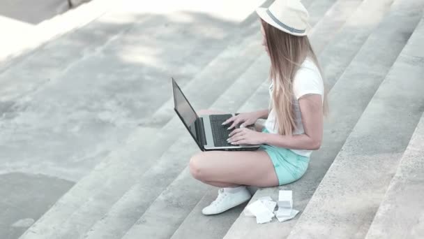 Mujer joven usando el ordenador portátil en los escalones al aire libre — Vídeo de stock