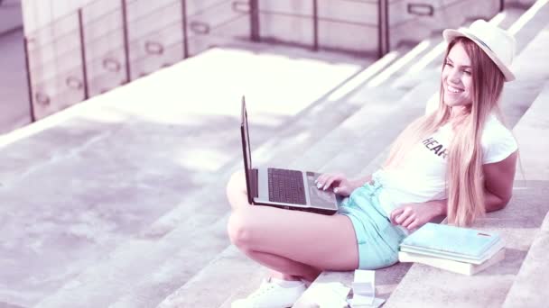 Ung kvinna med laptop på steg utomhus — Stockvideo