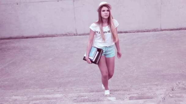 Retrato de una hermosa joven con bolso y libros caminando en el parque del campus — Vídeos de Stock