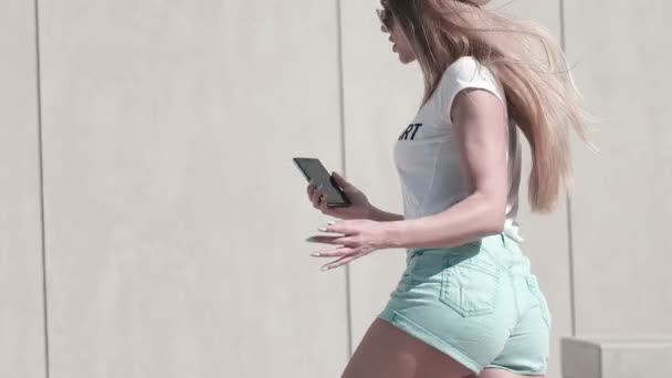 Привлекательная молодая женщина делает селфи со своим смартфоном в яркий солнечный день — стоковое видео