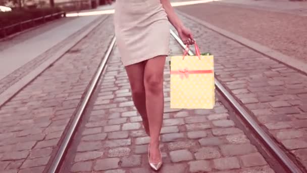 Heureuse jeune femme parlant au téléphone tout en marchant avec des sacs à provisions dans la ville — Video