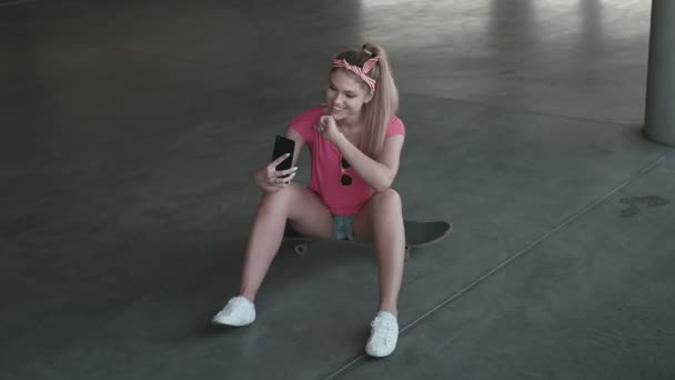 Aantrekkelijke skate jonge vrouw die een selfie van haarzelf met haar slimme telefoon in het parkeerterrein — Stockvideo