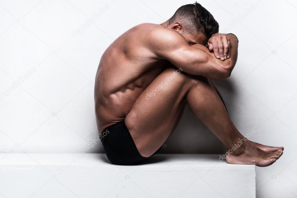 Muscular Man Sitting with Face Hidden Folded Arms