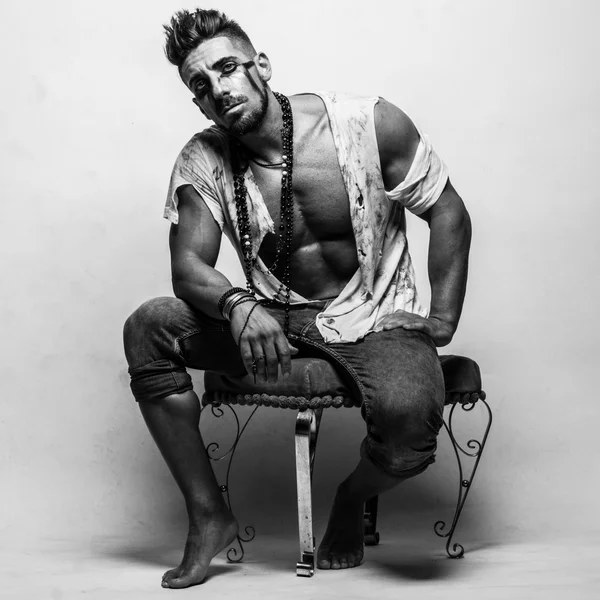 Muscular Man in Ragged Clothes Sentado en una silla —  Fotos de Stock