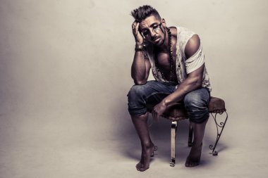 İskemlede düzensiz giysili kaslı adam