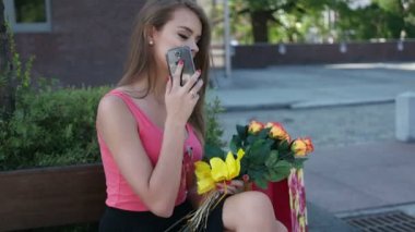 Şehirde bir demet çiçekle yürüyen bir genç.