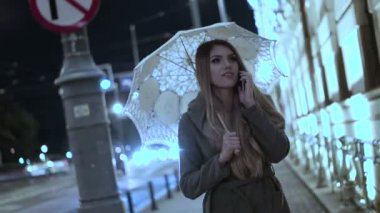 Mutlu kadın heyecan verici telefon sahip konuşmak holding şemsiye yağmurlu gün