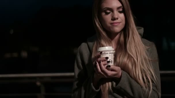 Chica adolescente en la calle por la noche bebiendo café y esperando — Vídeos de Stock