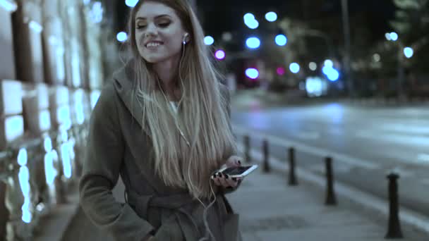 Woman listening music on cellphone walking evening time — Stock Video