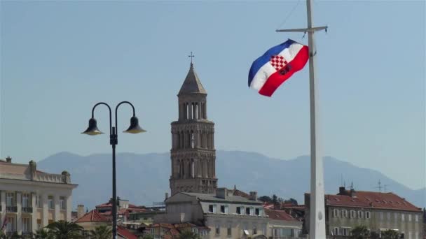 克罗地亚斯普利特市的长廊 以圣多姆尼乌斯钟塔和旧城分裂为背景的分裂长廊上的克罗地亚国旗 — 图库视频影像