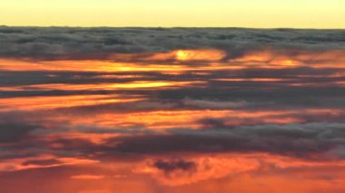 Bulutların üzerinde uçan; renkli yüksek irtifa günbatımı bulutları. Eşsiz, gerçek, hava görüntüleri. Kamera, uçağın havadaki doğal hareketini düzgünce takip ediyor..
