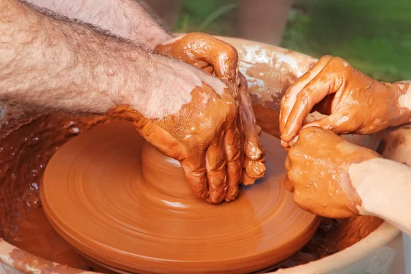 Potter and pupil hands on pottery wheel. — Stock Photo, Image