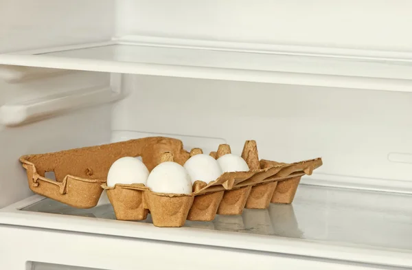 Яйца в бумажной коробке на полке холодильника . — стоковое фото