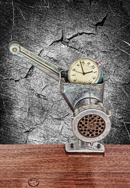 Small alarm clock in meat grinder on grunge monochrome background — Stock Photo, Image