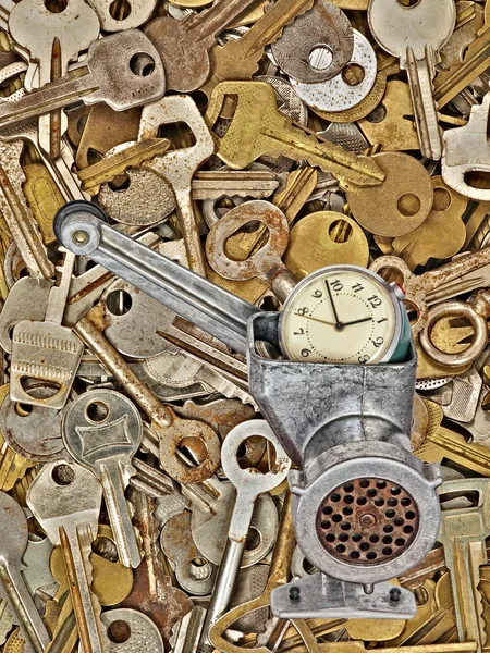 Alarm clock in meat grinder on old metal keys background. — Stock Photo, Image