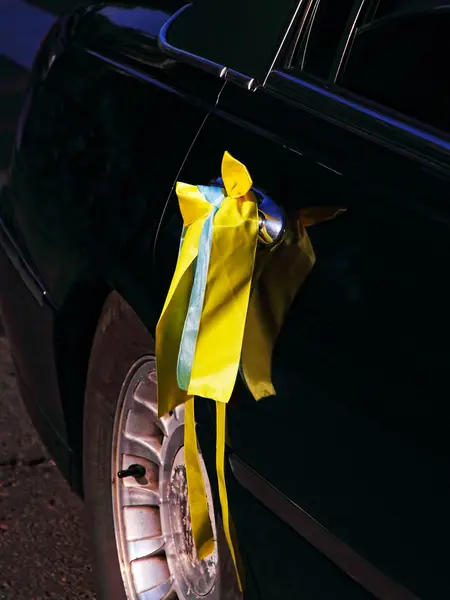 Ruban de mariage jaune sur porte de voiture noire . — Photo