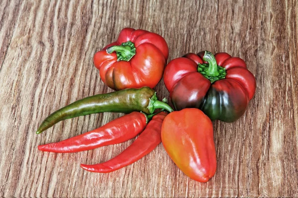 Různé druhy sladké a hot chili papričky na dřevěné pozadí. — Stock fotografie