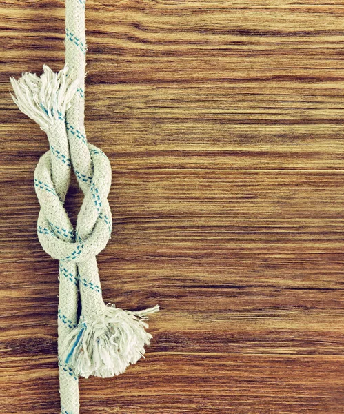 White rope and nautical reef knot on grunge wooden background.Empty space for text.