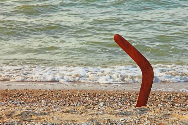 Australian Boomerang on sandy coastline near sea surf taken closeup.