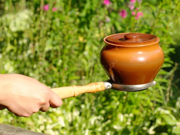 Ugn gaffel och lera potten med kvinna hand. — Stockfoto