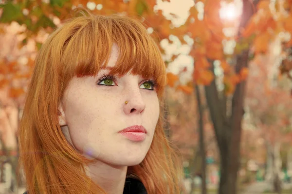 Pretty red hair girl face with freckles against red autumn folia — Stock Photo, Image