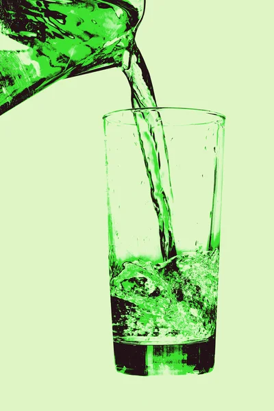 Kanne gießt auf Glas auf grünem Hintergrund. — Stockfoto