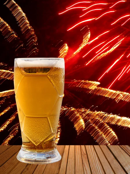 Bierglas auf Holztisch gegen buntes Feuerwerk. — Stockfoto