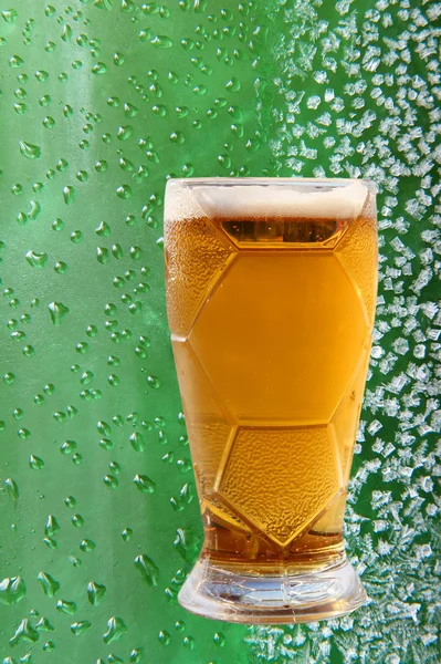Vidrio de cerveza espumosa sobre cristales de hielo y gotea fondo verde . —  Fotos de Stock