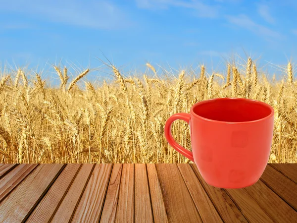 Taza de té rojo sobre superficie de madera contra espigas de trigo . —  Fotos de Stock