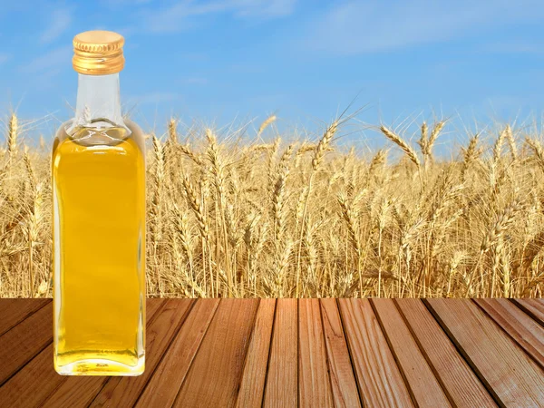 Vegetable oil on wooden surface against of golden wheat. — Stock Photo, Image