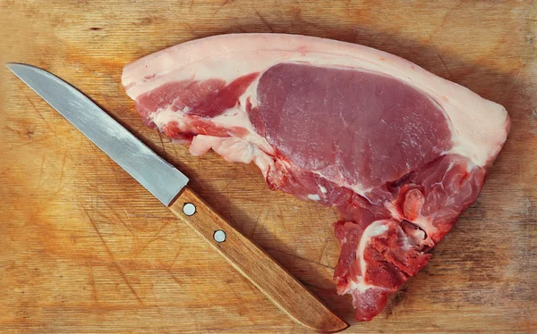 Сире свиняче м'ясо і ніж на дерев'яній обробній дошці . — стокове фото