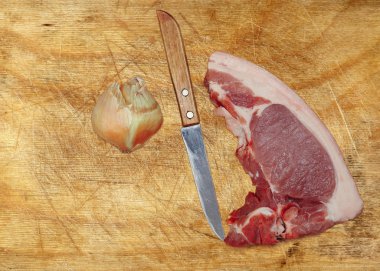 Çiğ domuz eti, bıçak ve soğan kesme tahtası üzerinde.